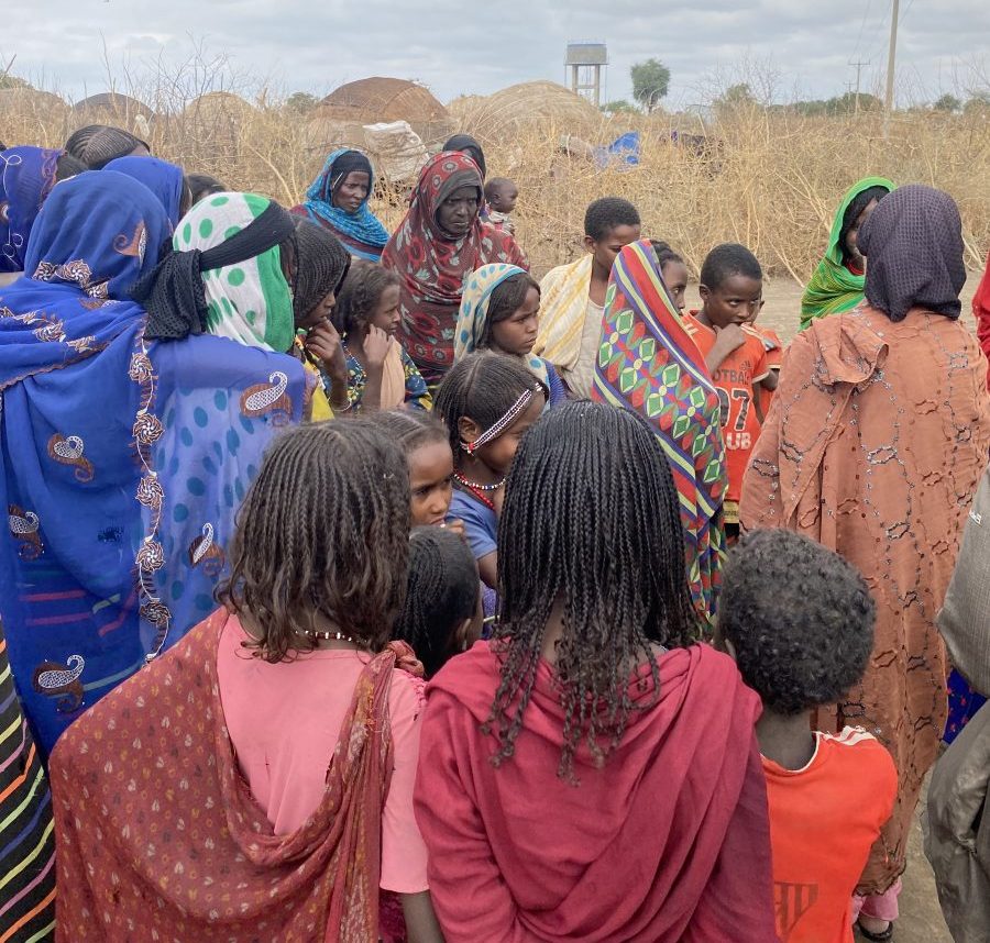 Women and girls gathered round listening to one woman speaking.